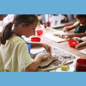 an over the shoulder photograph of a child hand-building with clay